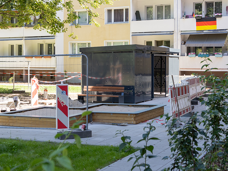 260624_Hof_2_WEB_IMG_2531 Die neue Buddelkiste und Fahrradgarage hinter einem Bauzaun.