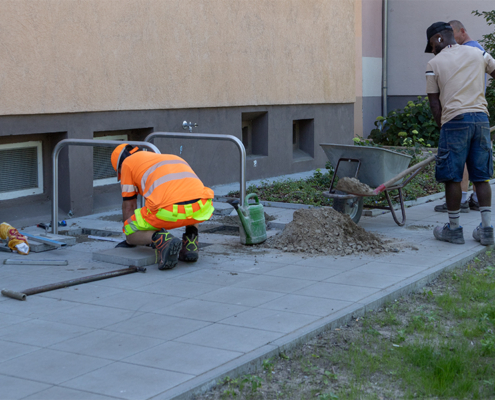 24.06.2026 // Fahrradbügel werden einbetoniert. 24.06.2026, ein Bauarbeiter verankert einen Fahrradbügel im Gehweg