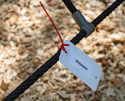 2.7.2026 // Wirbelwind 2.7.2026, Detailfoto von einer Kletternlage, Anhänger an einem Seil mit der Aufschrift Wirbelwind